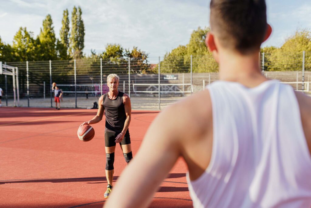 Basketballer Rainer und Julius stehen sich auf einem Feld draußen gegenüber