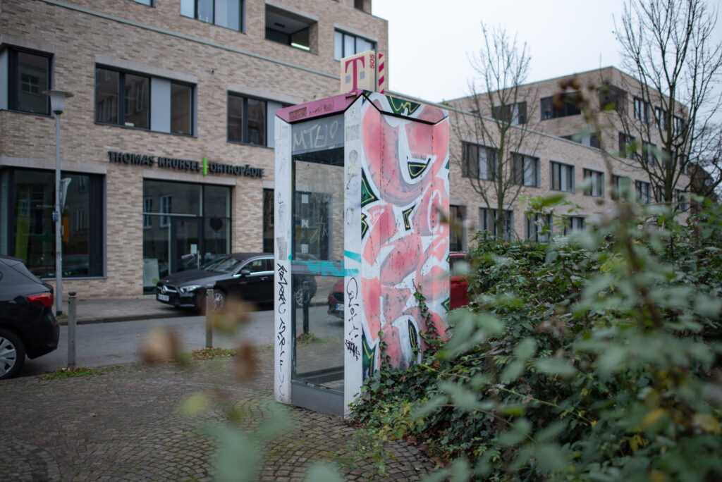 Telefonzelle, die an einer Seite mit rosa Grafitti besprüht wurde