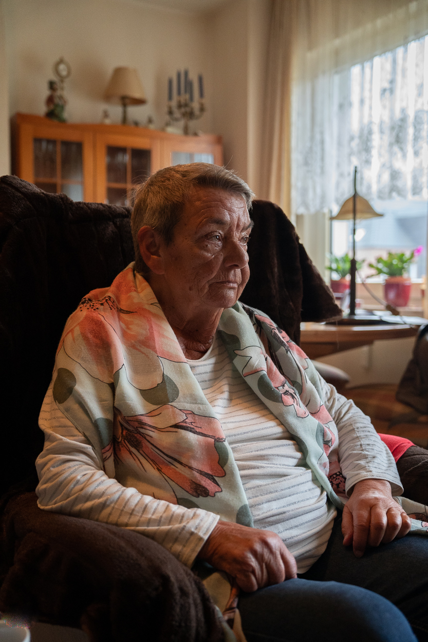 Christel Salmen sitzt in einem Sessel und schaut an der Kamera vorbei