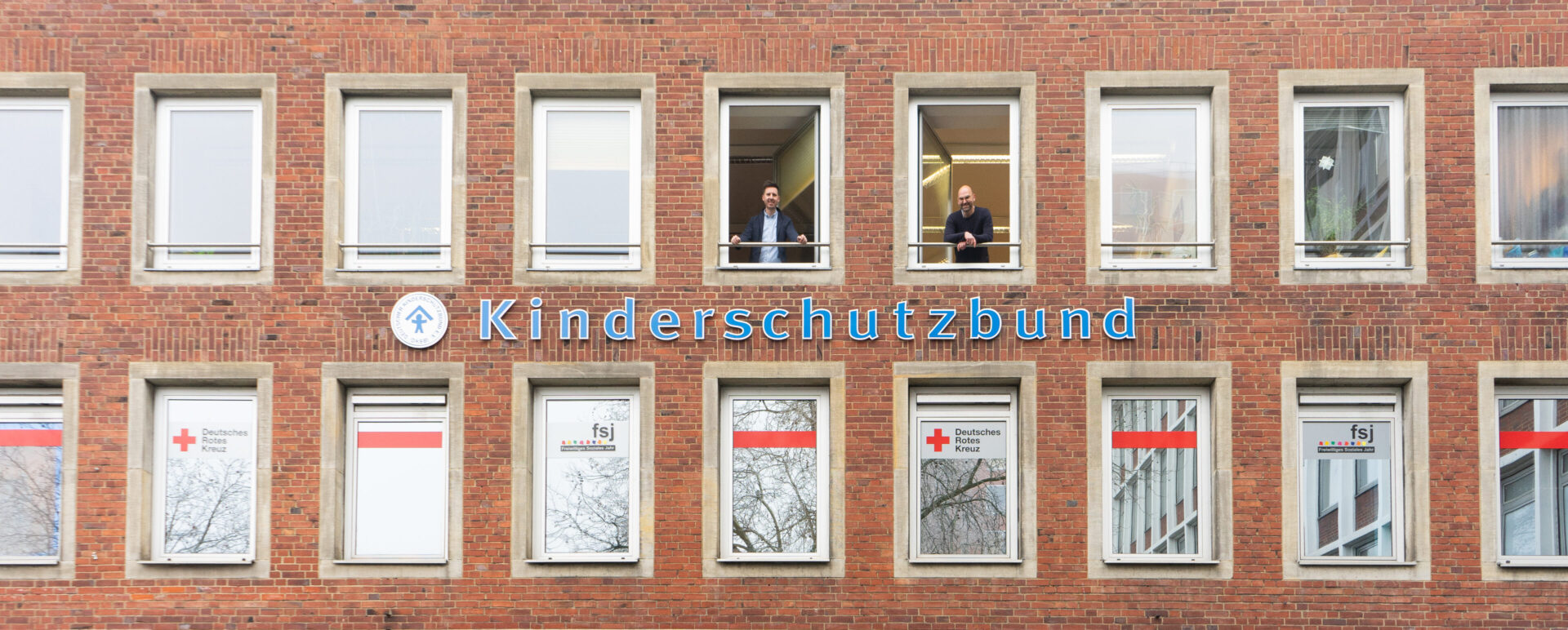 Christopher Heidbreder (l) und Torben Oberhellmann (r) schauen aus den Fenstern des Hauses des Kinderschutzbundes Münster